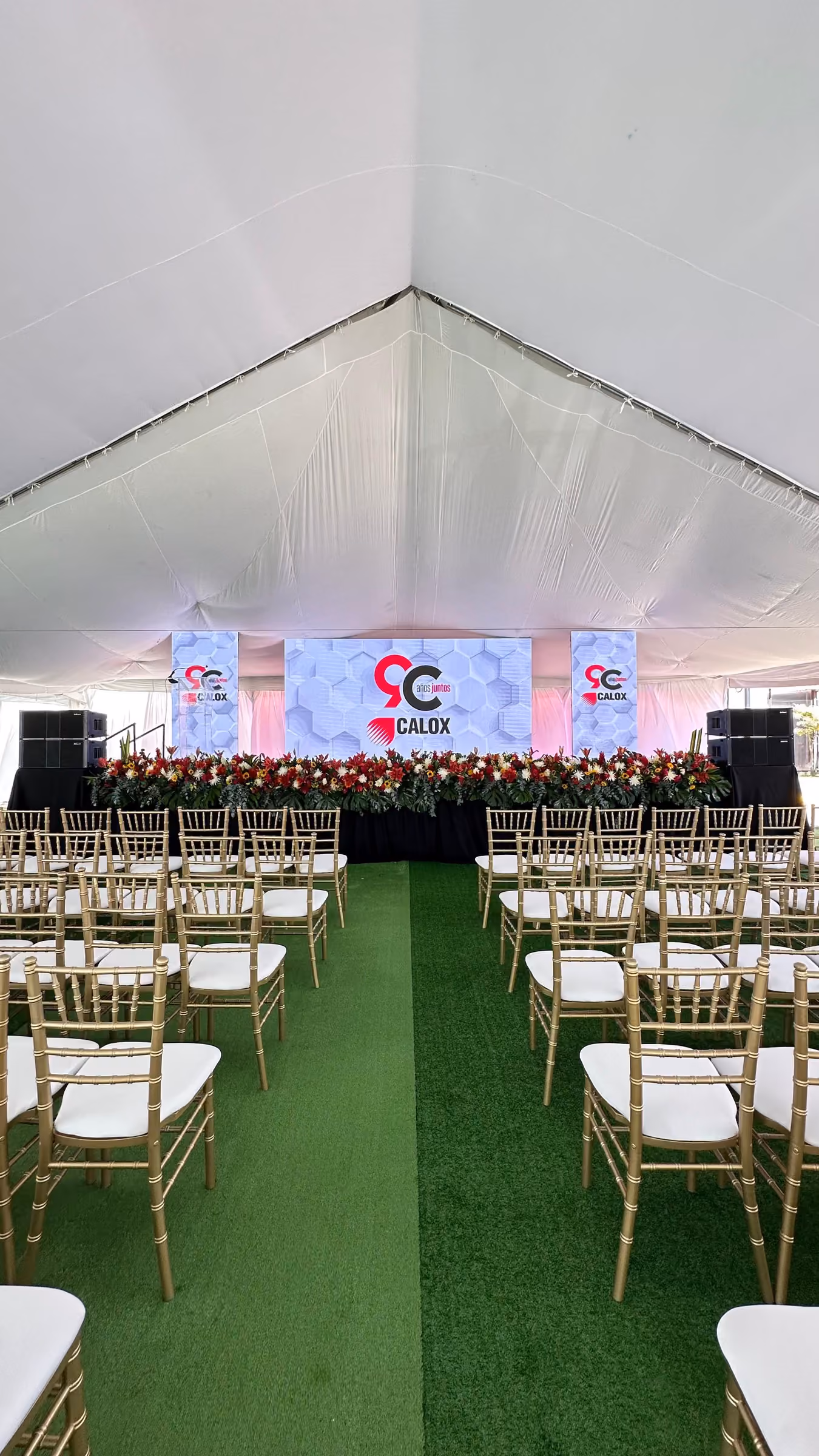 Carpa con escenario, pantallas LED y sillas doradas para un aniversario