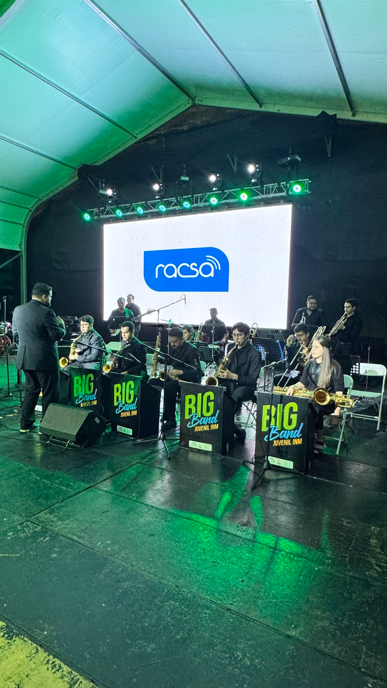 Big band en vivo frente a una pantalla LED bajo truss con luces verdes
