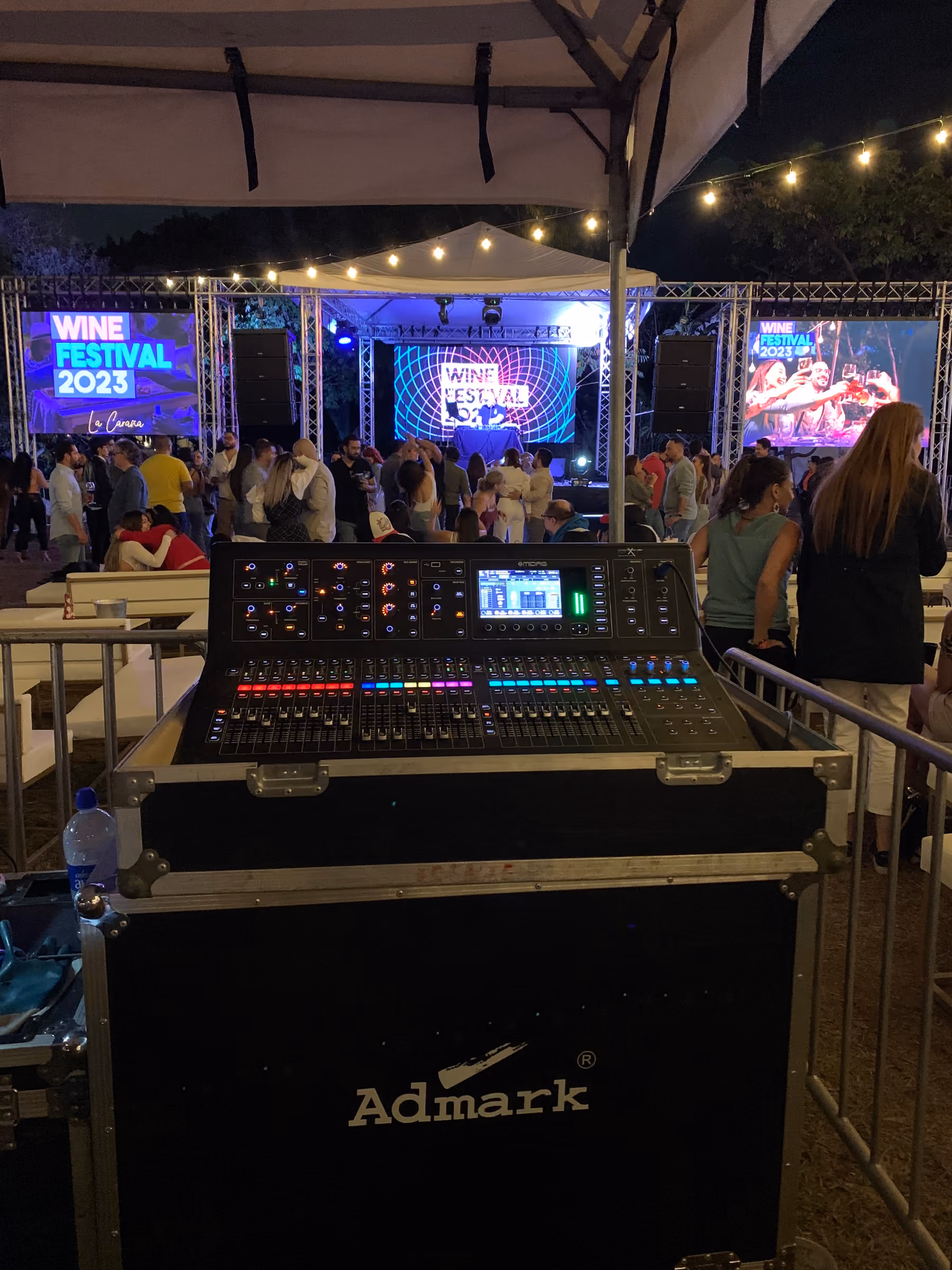 Consola de sonido frente al escenario de un festival nocturno al aire libre