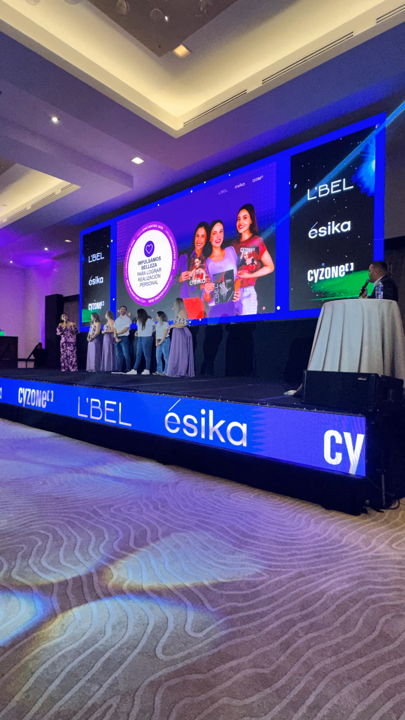 Escenario con pantallas LED y conductoras en un evento corporativo