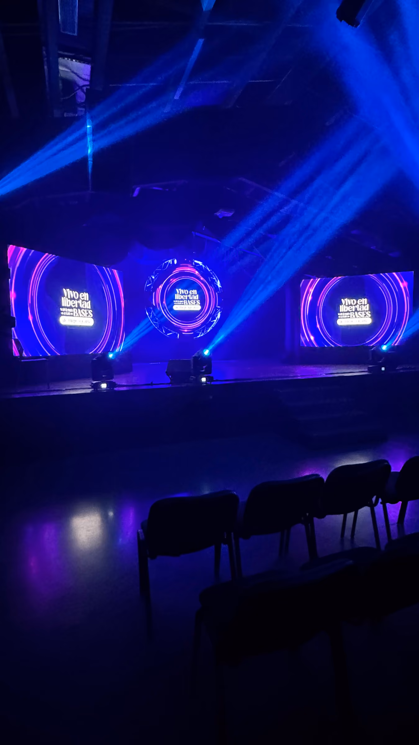 Escenario con tres pantallas circulares y haces de luz azul